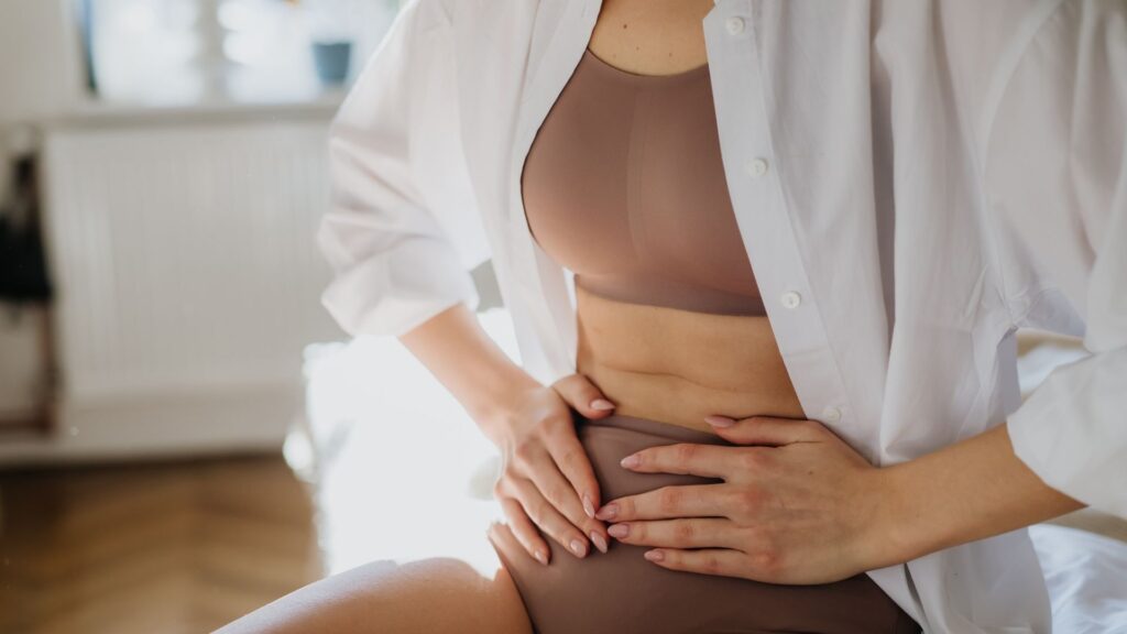 Frau hält sich den Unterleib – chronische Blasenentzündung natürlich behandeln