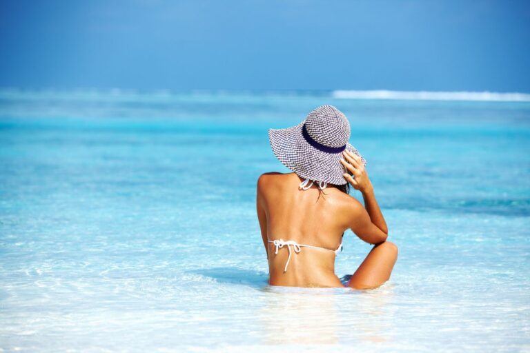 Frau mit Sonnenhut am Strand – natürlicher Sonnenschutz im Sommer