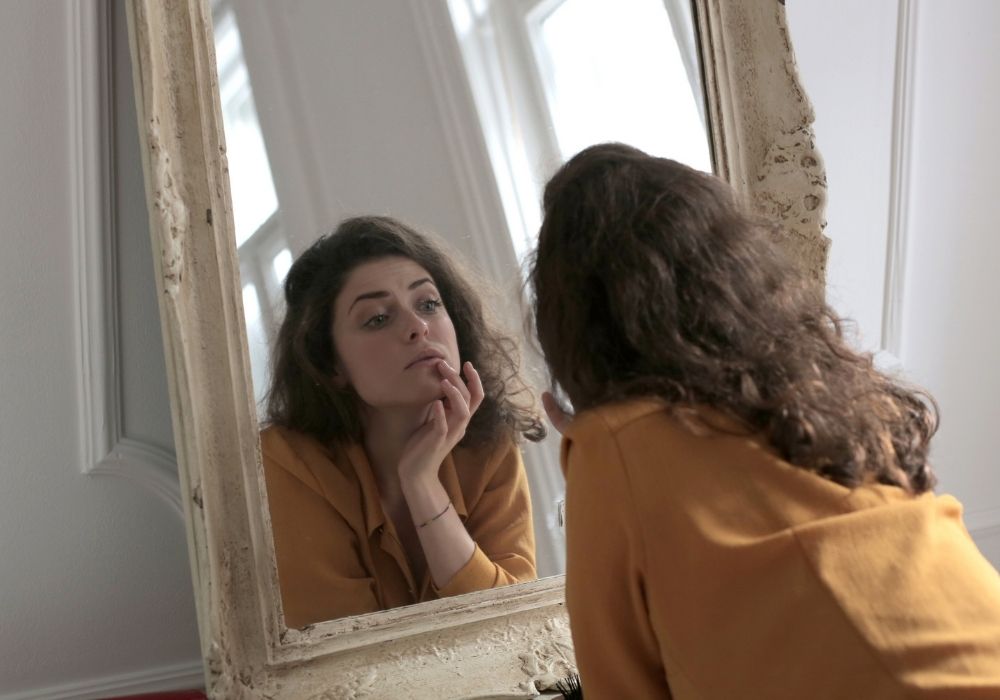 Frau blickt skeptisch in den Spiegel